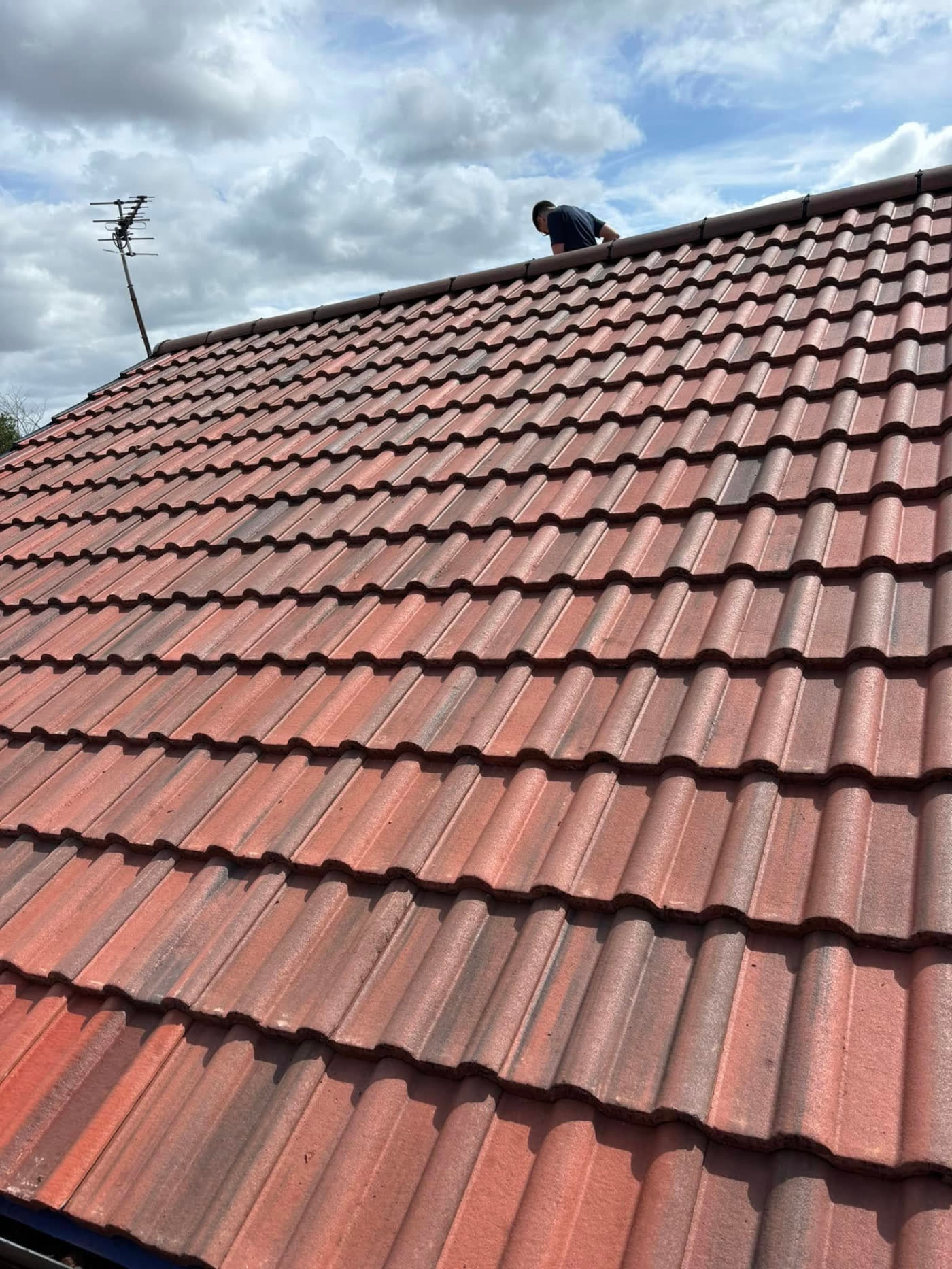 Roofer bedding ridge tiles on a re-tiled pitched roof during a roof repair by MB Roofline & Joinery in Bury
