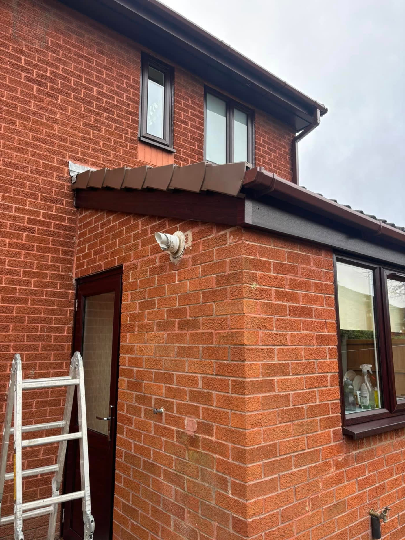 Brown uPVC guttering and downpipe replaced on a red-brick house by MB Roofline & Joinery in Bury